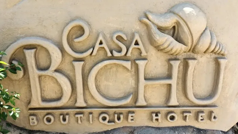The sign for Casa Bichú Hotel Boutique, with a seashell above the words, set out on a sand-coloured slab affixed to the wall