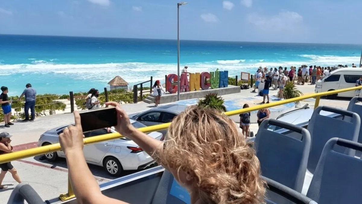 Woman photographing the Cancun sign on the beach promenade in Cancun, Mexico 