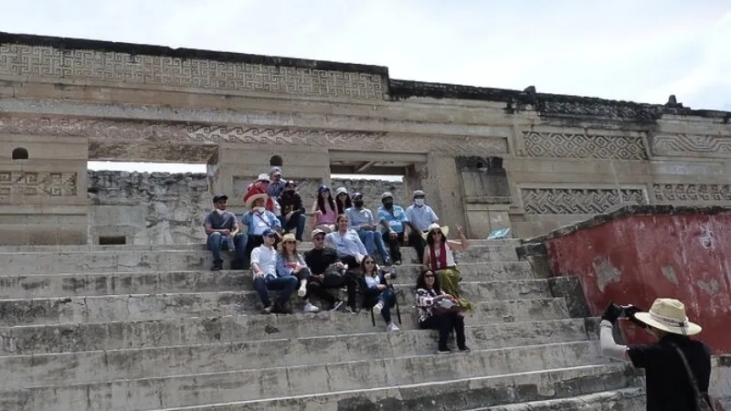 A tour group being photographed before the ruined city of Mitla in Oaxaca, Mexico