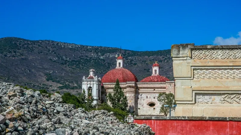 The ruined city of Mitla and the Templo de San Pablo Apóstol in San Pablo Villa de Mitla in Oaxaca, Mexico, with the Sierra Norte mountains in the background
